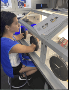 Girl sits at a box inside a spacecraft to complete an experiment.