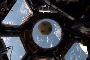 Shane Kimbrough/NASA An old practice soccer ball with faded signatures from players on the 1986 Clear Lake girls' team floats in the cupola of the International Space Station in 2016.